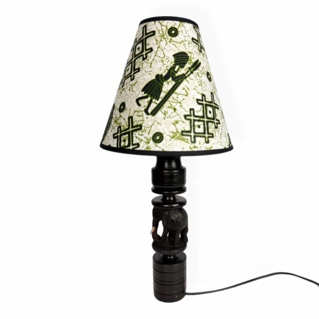 Afrykańska lampa stołowa z hebanową podstawą Makonde ze słoniem i abażurem z tkaniny Chitenge z motywami afrykańskich masek i symboli.
