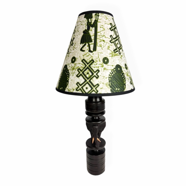 Afrykańska lampa stołowa z hebanową podstawą Makonde ze słoniem i abażurem z tkaniny Chitenge z motywami afrykańskich masek i symboli.